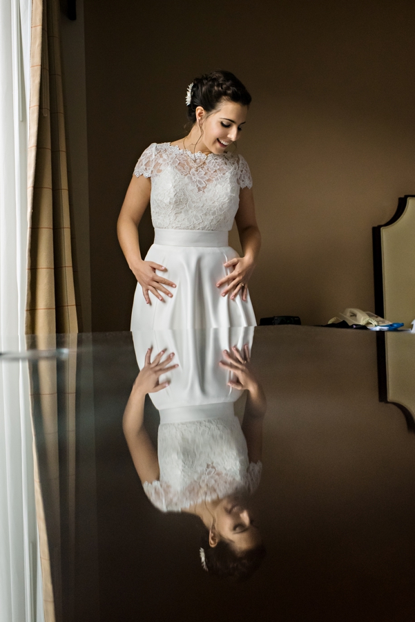 A bride smiles looking at her wedding dress.